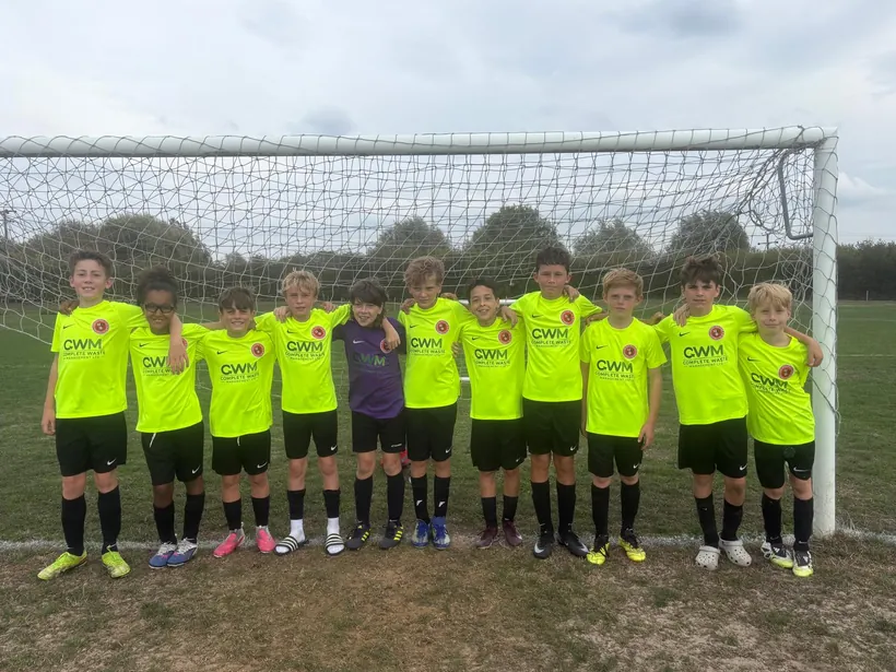 The Byron Red Star FC Under 11s team in CWM Complete Waste Management shirts, standing in front of a goal.